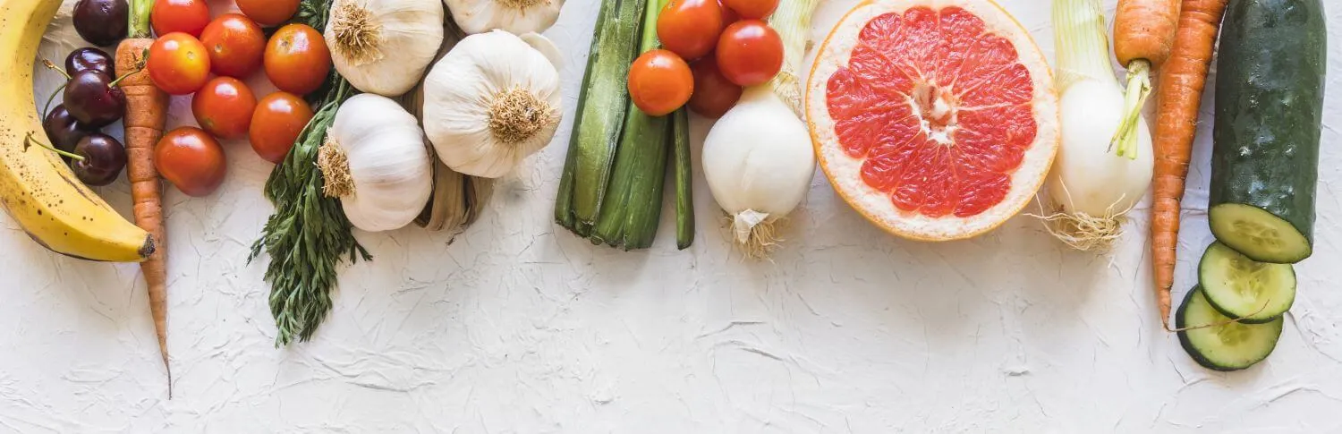 Tomatoes, garlic, carrots, onions, and cucumber laid out for the kitchen